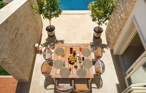 A patio with a wooden table, wicker chairs, and potted plants. - Beautiful home in Vabriga (Vabriga)