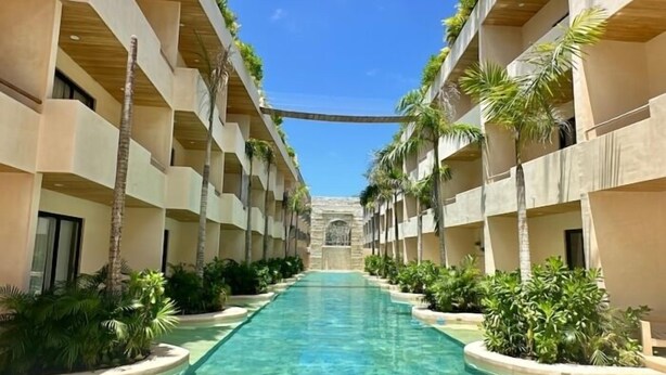A hotel corridor with a central pool flanked by balconies and lush greenery. - COCAY 218, Studio with Pool & Tropical Vibes (Tulum)