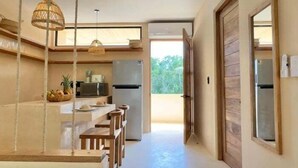 A modern kitchen with a central island, wooden chairs, and a hanging light fixture. - COCAY 218, Studio with Pool & Tropical Vibes (Tulum)