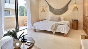 A modern bedroom with a large bed, two bedside tables, a round wooden table with a vase, and a balcony with curtains. - COCAY 218, Studio with Pool & Tropical Vibes (Tulum)