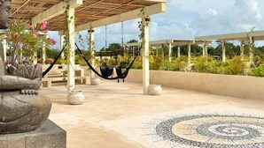 A serene outdoor area with a stone Buddha statue, a hammock, and a patterned floor. - COCAY 201, Swim Up, Serenity & Sun (Tulum)