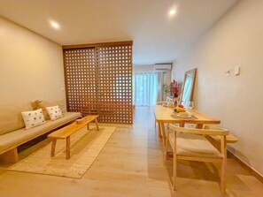 Ein modernes Wohnzimmer mit einer Couch, einem Holztisch und einem Essbereich mit Tisch und Stühlen.