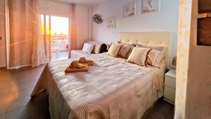 Un dormitorio con una cama grande, una mesita de noche, una ventana con cortinas y vistas al exterior.