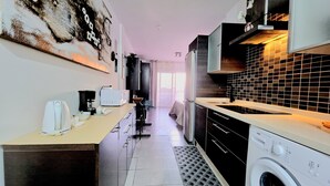 Una cocina moderna con lavadora, cafetera y microondas.