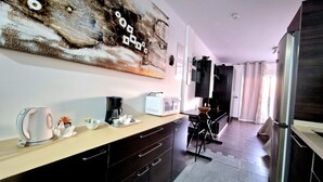 Una cocina moderna con cafetera, microondas y un cuadro abstracto de gran tamaño en la pared.