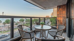 A balcony with wicker chairs, a glass table, and a potted plant. - Iracema Residence #103 - Seafront by Carpediem (Fortaleza)