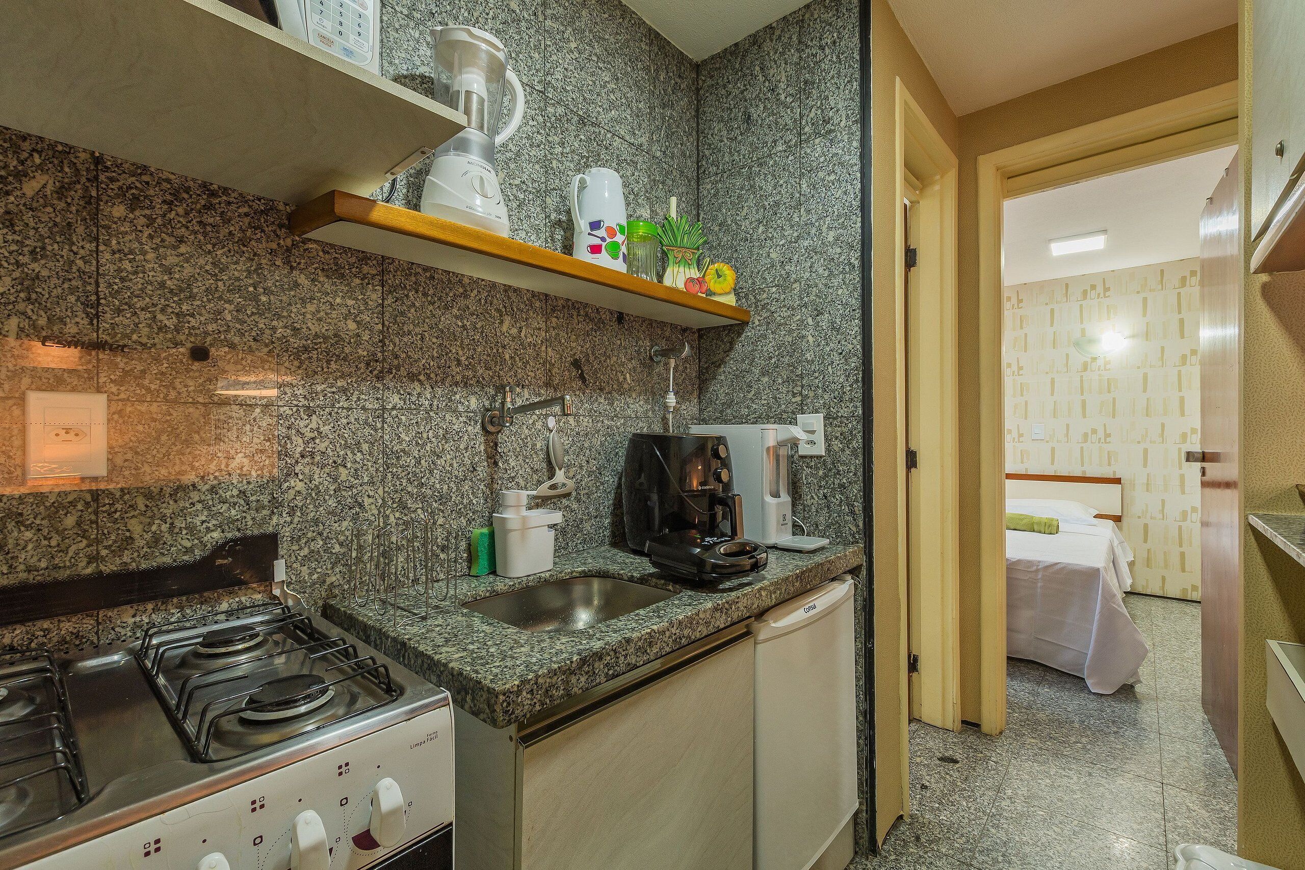 A compact kitchen with granite countertops, a gas stove, a coffee maker, and a dishwasher.