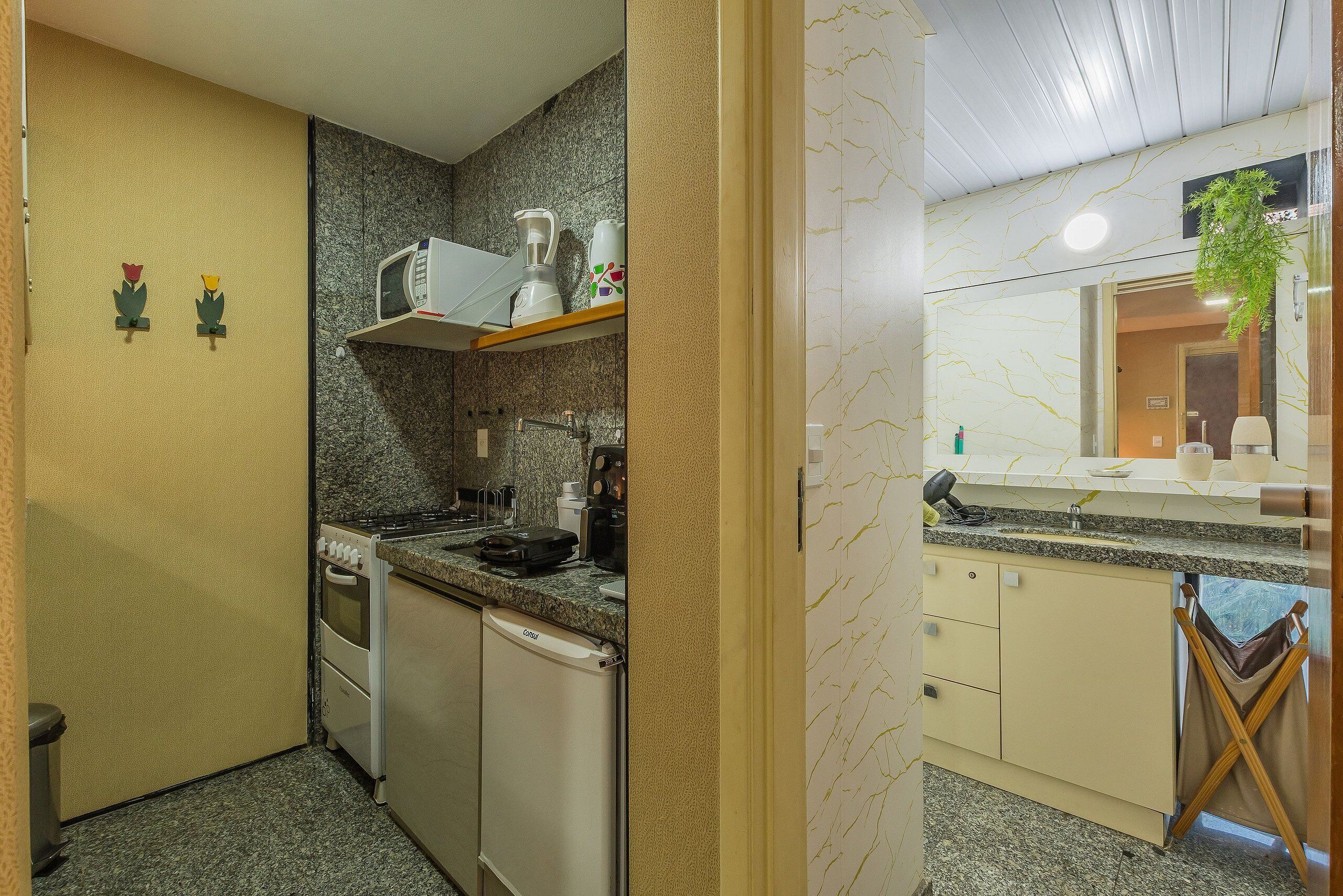 A compact kitchen with a built-in oven, dishwasher, and a microwave on a shelf.