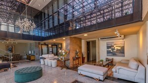 A spacious lobby with a high ceiling, a chandelier, and a large window overlooking a terrace. - Iracema Residence #103 - Seafront by Carpediem (Fortaleza)