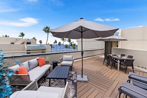 Eine Dachterrasse mit Esstisch, Stühlen, einer Couch und einem Sonnenschirm.