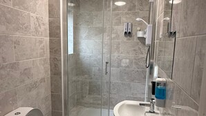 A modern bathroom with a glass-enclosed shower, a toilet, a sink, and a mirror. - Family Bedroom with Attached Bathroom in Blackpool-Families and Couplies Only (Preston)