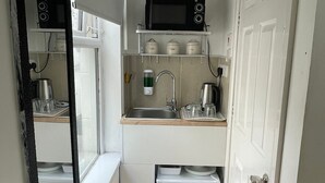 A compact kitchen with a microwave, sink, and storage cabinets. - Family Bedroom with Attached Bathroom in Blackpool-Families and Couplies Only (Preston)