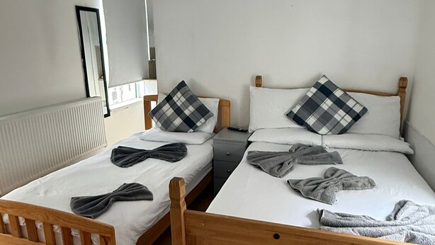 A room with two wooden beds, each with a pillow and a blanket. - Family Bedroom with Attached Bathroom in Blackpool-Families and Couplies Only (Preston)