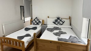 A small, clean room with two wooden beds, white bedding, and a mirror on the wall. - Family Bedroom with Attached Bathroom in Blackpool-Families and Couplies Only (Preston)