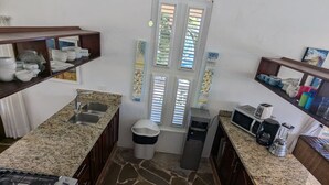 Una cucina compatta con piani di lavoro in granito, un fornello a gas, un cestino, un forno a microonde e un dispenser per l'acqua.