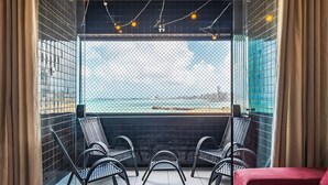 A balcony with a view of the sea, featuring a red sofa and three wicker chairs. - Aquidaba #803 - Apto With sea View by Carpediem (Fortaleza)