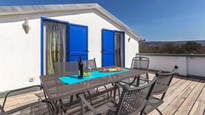 A rooftop terrace with a table set for dining, featuring a bottle of wine and a fruit platter. - Lovely apartment in Trget (Trget)