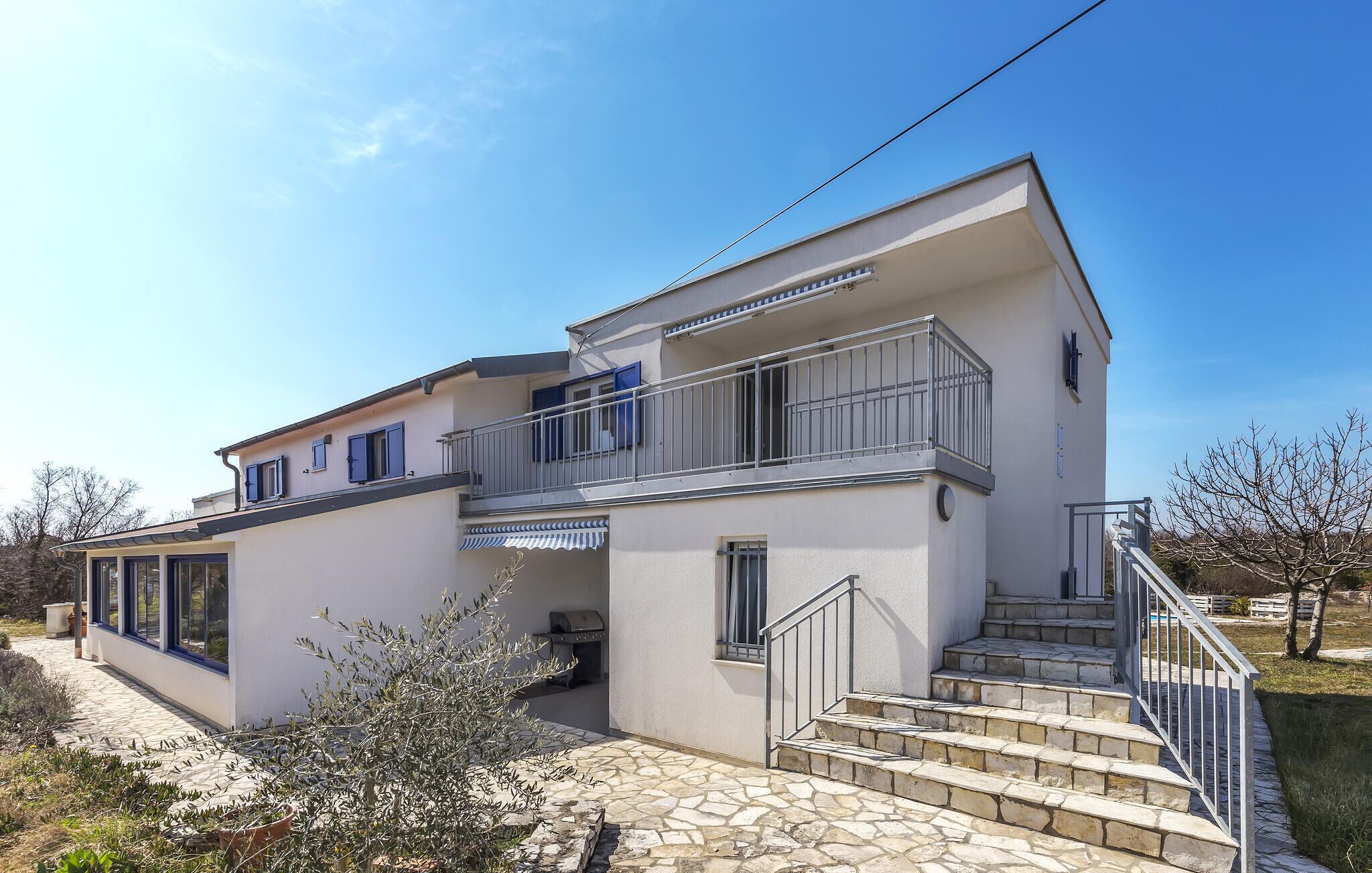 Ein zweistöckiges Haus mit Balkon, Steinstufen und blauem Himmel.
