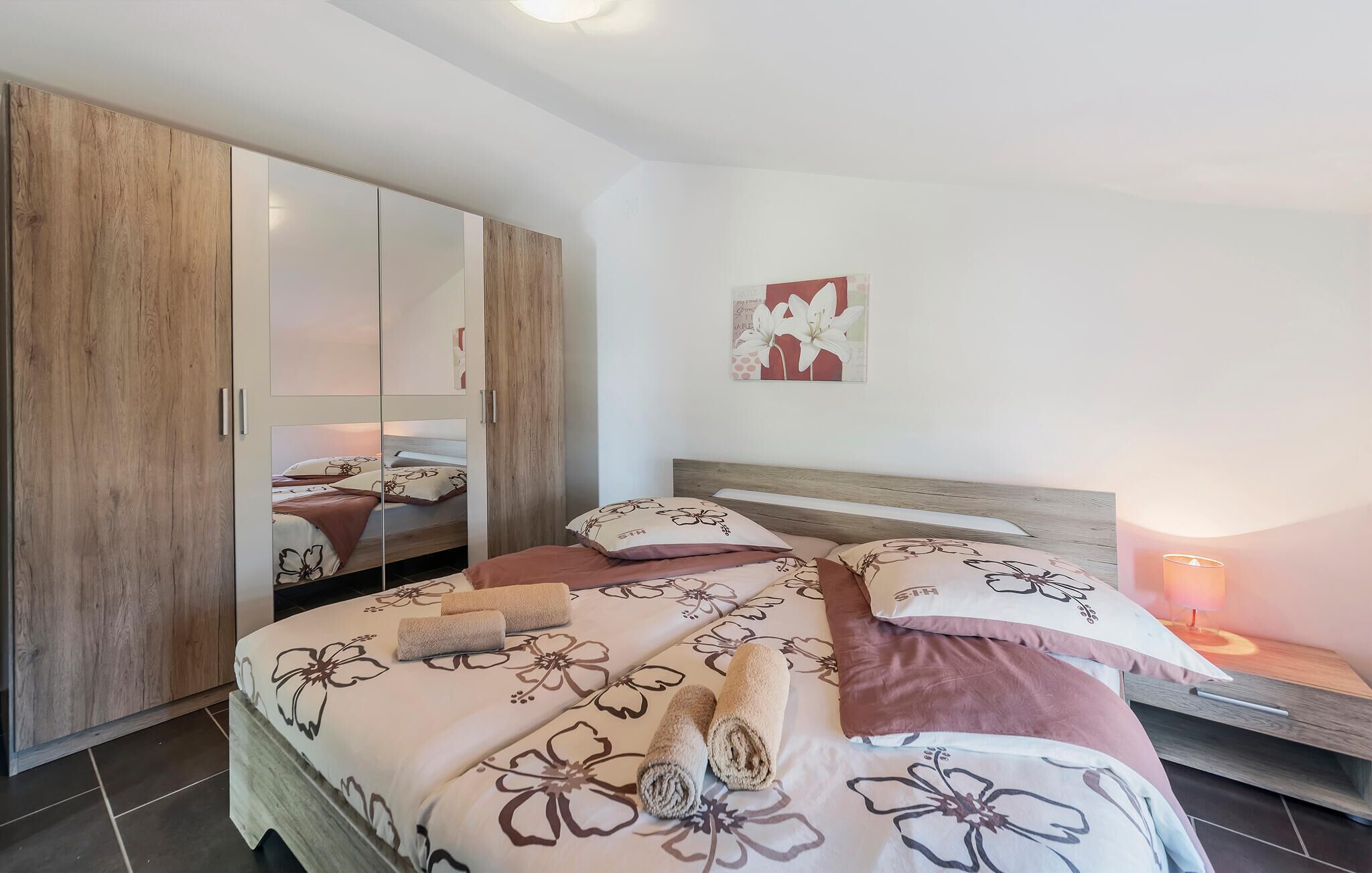 A bedroom with a bed, a wardrobe, a nightstand, and a wall art piece.