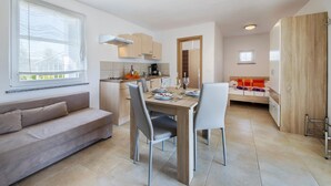 A modern apartment with a dining area, kitchenette, and a living room with a sofa. - Lovely apartment in Trget (Trget)