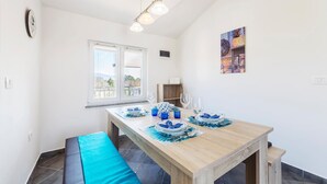 A dining area with a wooden table set for two, a bench, and a view of the outdoors through a window. - Lovely apartment in Trget (Trget)