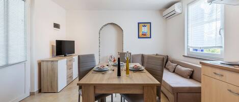 Une cuisine moderne avec un coin repas, comprenant une table en bois, un four encastré et un téléviseur.