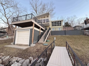Ein modernes, zweistöckiges Haus mit Garage, einer Holzdiele und einer Steinmauer.