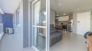 Eine moderne Wohnung mit Balkon, einem grauen Sofa und einer Küchenzeile.