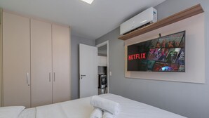 Ein Hotelzimmer mit einem Bett, einem an der Wand montierten Fernseher, der Inhalte von Netflix zeigt, und einem Wasserspender.