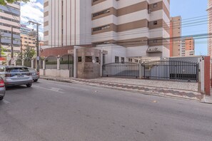 Ein modernes Gebäude mit geschlossenem Eingangsbereich, einem Schild mit der Aufschrift "Hamilton Hotel" und einem Parkplatz mit parkenden Autos.