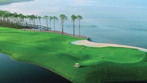 Ein Golfplatz mit einem Wasserhindernis, Sandbunkern und Bäumen.