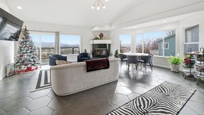 Een ruime woonkamer met een witte bank, een open haard en een groot raam met uitzicht op een stadsbeeld.