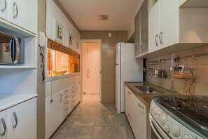 Eine Küche mit weißen Schränken, einem Herd und einem Kühlschrank.