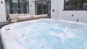 Un bain à remous avec un canapé en osier et des portes en verre.