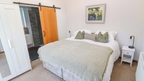 Une chambre à coucher comprenant un lit, une table de chevet, une lampe, un tableau, une armoire et une porte coulissante.