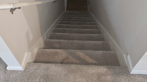 A narrow stairway with carpeted steps leading to a landing.