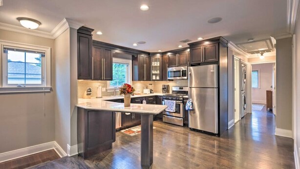A modern kitchen with dark wood cabinets, stainless steel appliances, and a central island.