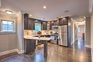 A modern kitchen with dark wood cabinets, stainless steel appliances, and a central island.