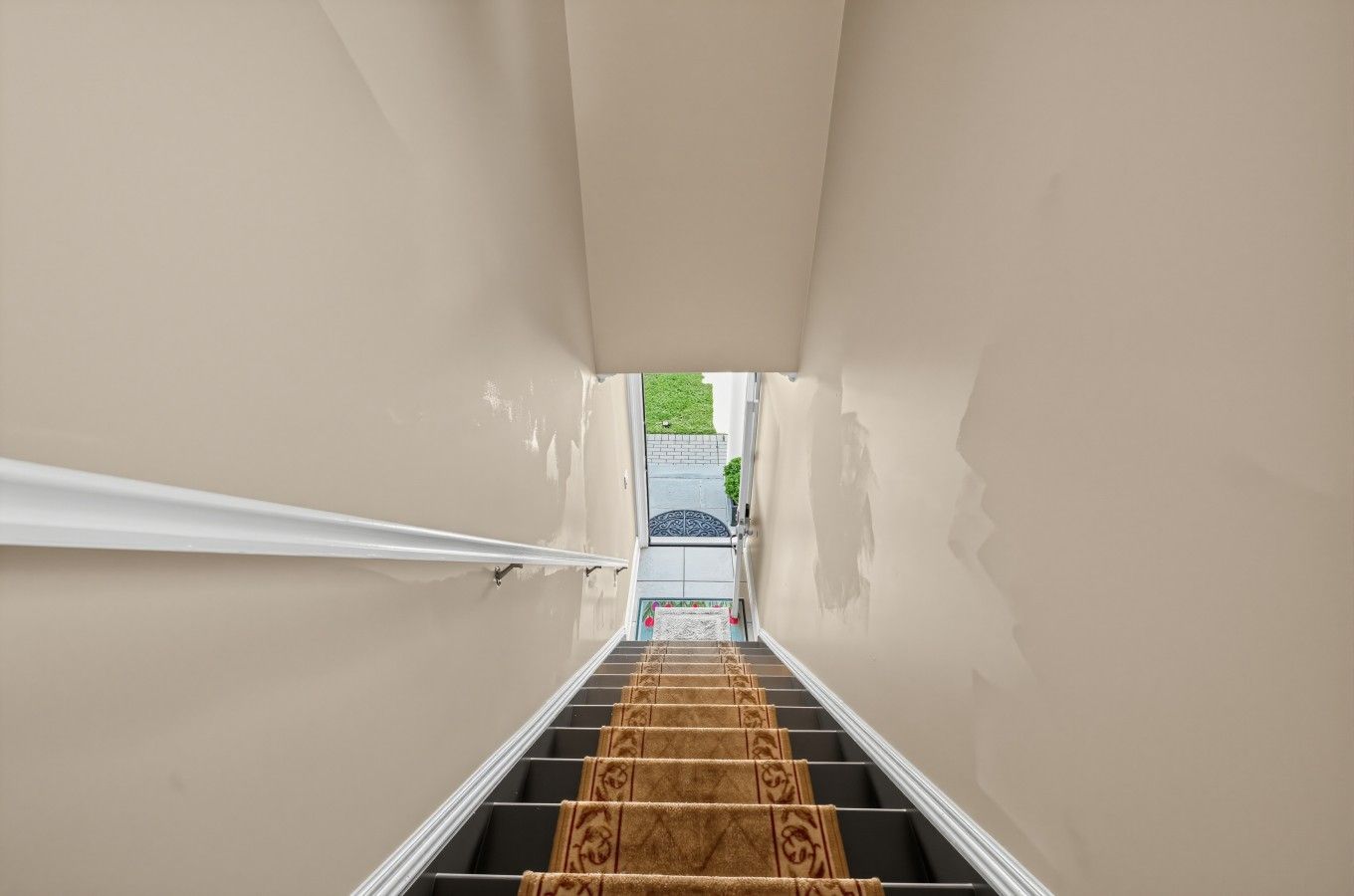 Un escalier avec une rampe et une moquette à motifs menant à une porte.