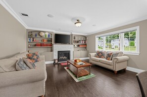 Ein Wohnzimmer mit Kamin, zwei Sofas, einem Couchtisch und einem Bücherregal.