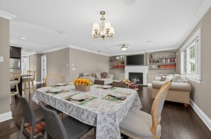 A dining area with a table set for four, a chandelier, and a fireplace in the background. - Cozy Glen Cove Apt Near Ferry, Parking & NYC! (Glen Cove)