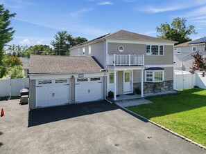Ein zweistöckiges Haus mit Garage, überdachter Veranda und gepflegtem Rasen.