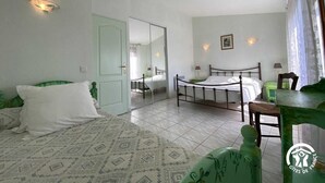 Une chambre avec deux lits, une chaise verte, une table et un miroir.