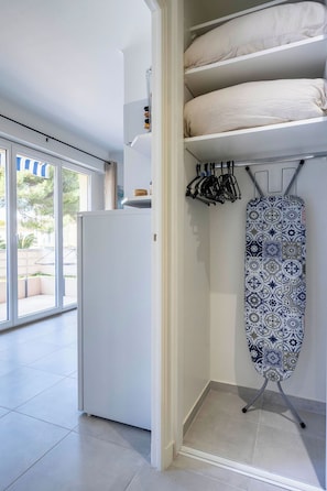 A modern kitchen with a built-in refrigerator, a hanging rack for kitchen utensils, and a patterned ironing board. - L'Harmonie de Carnot avec Balcon (Cannes)