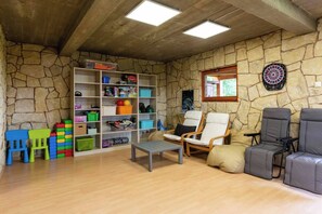 A room with a stone wall, a dartboard, a bookshelf, and two chairs. - House with a View, Mucharz 405 (Mucharz)
