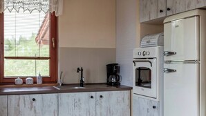 Una cuina amb finestra, vàlibes, cafetera, forn i nevera.