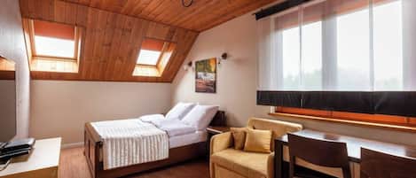 Un dormitorio con cama, sofá, escritorio y ventana con vistas.
