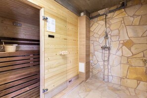 Un sauna avec des murs en bois, un mur en pierre et un espace douche.