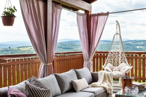A balcony with a sofa, hanging chair, and potted plant. - House with a View, Mucharz 405 (Mucharz)