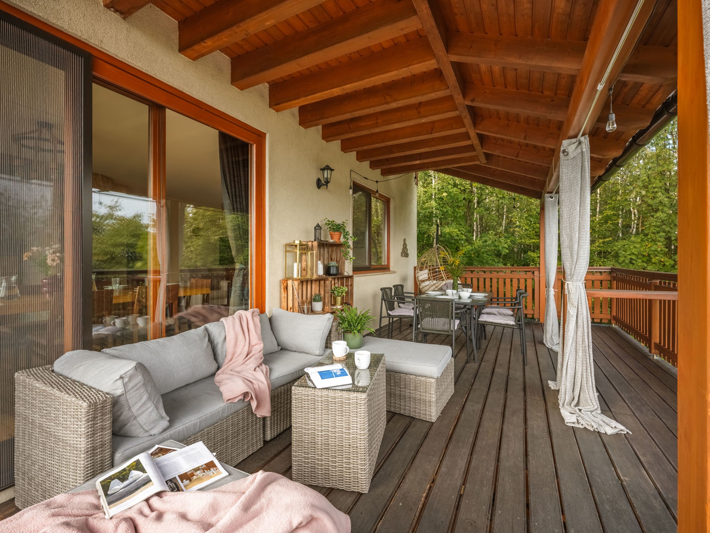 A covered outdoor seating area with wicker furniture, a sofa, and a table.